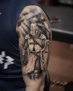 a man with a cross and armor tattoo on his arm