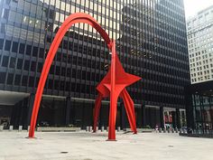 a large red sculpture in front of a tall building