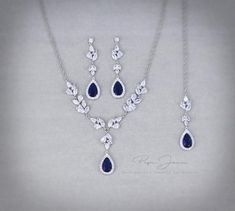 a necklace and earring set with blue stones on a gray background, in the shape of teardrops