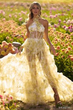 a woman wearing a yellow dress standing in a field full of pink and white flowers