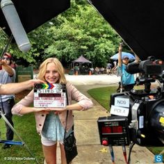 a woman holding up a camera in front of a group of people