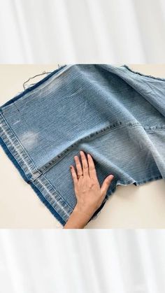 a woman's hand is touching the bottom of a pair of jeans that have been folded over