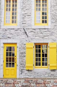 an old brick building with yellow windows and shutters