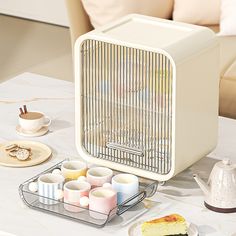 a table topped with cups and cakes next to a toaster on top of a table