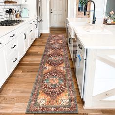 a long rug is in the middle of a kitchen with white cabinets and counter tops