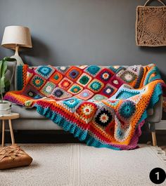 a crocheted granny blanket on a couch in a living room next to a lamp