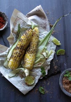 grilled corn on the cob with limes and seasoning next to it