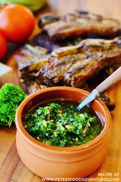 a small bowl filled with green sauce next to some meat