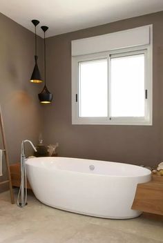 a white bath tub sitting under a window next to a ladder in a room with two windows