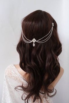 the back of a woman's head wearing a silver chain and crystal hair piece