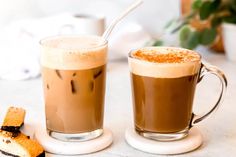 two mugs of coffee sitting next to each other on a table