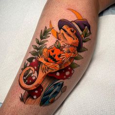 a lizard wearing a hat and holding a pumpkin on top of it's leg