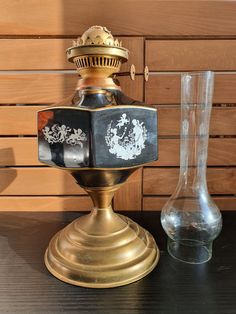 an old fashioned oil lamp next to a glass vase