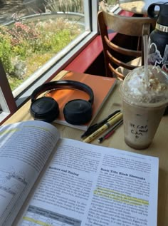 an open book sitting on top of a table next to a cup of coffee