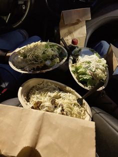 two plates of food sitting in the passenger seat of a car next to a paper bag