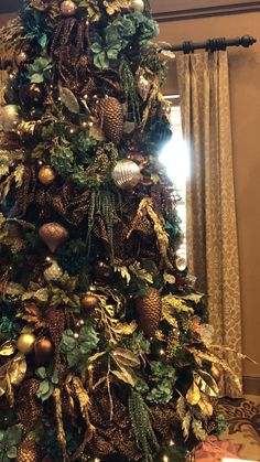 a christmas tree is decorated with gold and green ornaments, including pineconi leaves