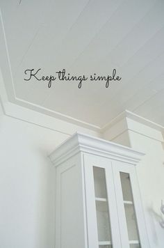 there is a white cabinet with writing on the wall above it that says, keep things simple