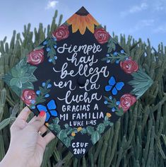 someone holding up a graduation cap with flowers on it