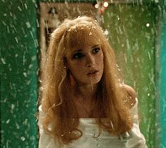 a woman standing in front of a mirror with snow falling down on her face and hair