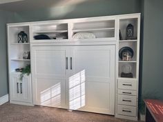 a large white bookcase with doors and drawers in a room that has carpeted flooring