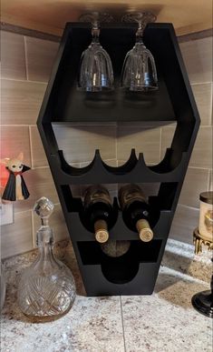 two wine glasses are sitting on top of a shelf with three bottles in it and one is empty