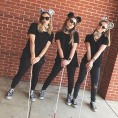 three girls dressed up as mouse ears and holding golf clubs in front of a brick wall