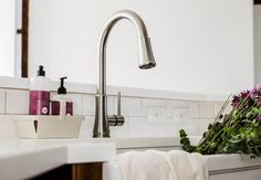 a kitchen sink with flowers and soap on the counter