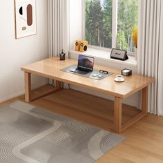 a laptop computer sitting on top of a wooden desk in front of a large window