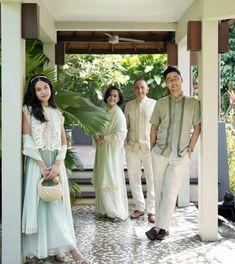 a group of people standing next to each other in front of a house with plants