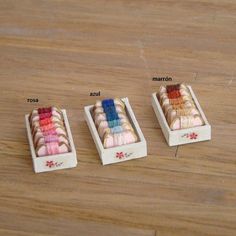 three small wooden boxes with different colored yarns in them sitting on a wood surface