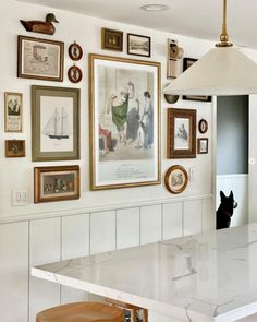 a kitchen with pictures on the wall and a stool in front of it that is underneath a lamp