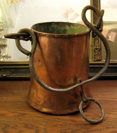 an old metal cup with a handle on a wooden table