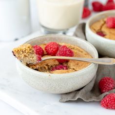 a bowl filled with raspberries and oatmeal next to a glass of milk