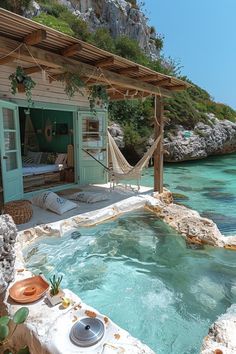 an outdoor hot tub with hammock in the water next to a beach house