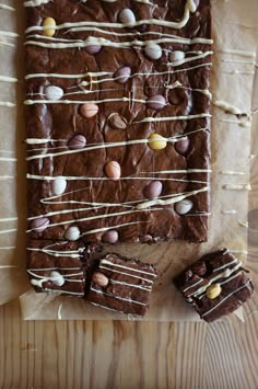 a chocolate dessert with white icing and sea shells on it, next to two pieces of brownie