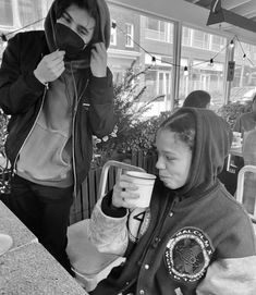 a woman in a black hoodie holding a coffee cup