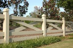 a white picket fence with grass and trees in the background