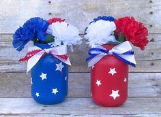 two red, white and blue vases with flowers in them sitting on a wooden surface