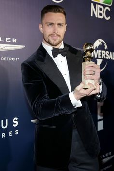 a man in a tuxedo holding an award for his role in the show