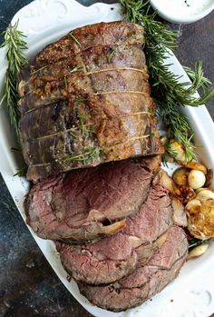 roast beef with rosemary garnish and potatoes on a platter, ready to be served