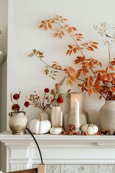 an arrangement of flowers and candles on a mantel in front of a white fireplace