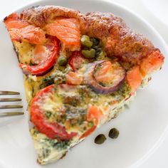 a white plate topped with a slice of pizza covered in veggies and sauce