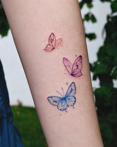 two colorful butterflies on the left side of the arm, one purple and one blue