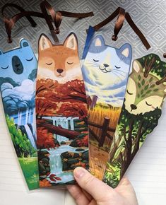 hand holding four bookmarks with cats on them