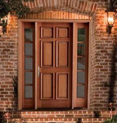 a wooden door is shown in front of a brick building with two lights on the side