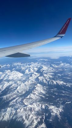 the wing of an airplane flying over snow covered mountains