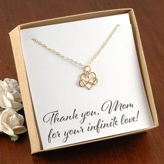 a thank you mom necklace in a gift box next to a white rose on a wooden table