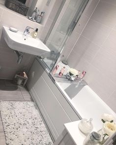 a bathroom with a sink, mirror and bathtub next to a rug on the floor