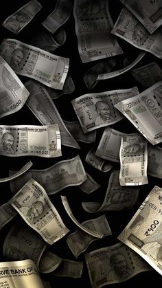 money falling down into the air and on top of a pile of other bills in front of a black background