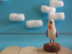 a small toy bird sitting on top of a piece of wood